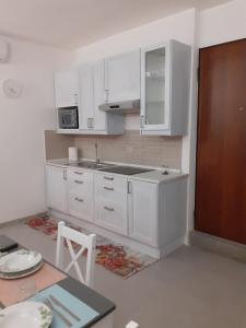 - une cuisine blanche avec des placards blancs et une table dans l'établissement Home Sweet Home, à Castel SantʼElia