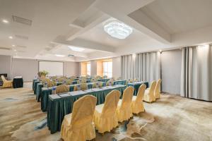 Holiday Inn & Suites Suzhou Yangcheng Lake, an IHG Hotel في سوتشو: غرفة فيها صفوف من الطاولات والكراسي