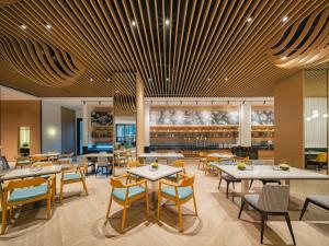 a restaurant with tables and chairs and a bar at Holiday Inn & Suites Suzhou Yangcheng Lake, an IHG Hotel in Suzhou