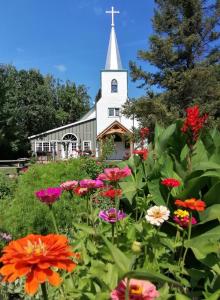 a church with a field of flowers in front of it at Rosedale Chapel Bed and Breakfast in Steinbach