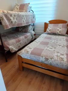 a bedroom with two beds and a wooden floor at Casa a 5 minutos del balneario in Frutillar