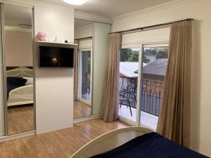 カネラにあるcasa em condominioのベッド、テレビ、バルコニーが備わる客室です。