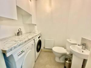 a white bathroom with a washing machine and a sink at 3 Bedrooms House in Manchester in Manchester