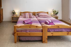 ein Holzbett mit lilafarbener Bettwäsche und Kissen darauf in der Unterkunft VILLA 50 personnes avec piscine et terrain de tennis et Basket in Diemeringen