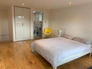 a bedroom with a white bed and a yellow chair at Luxury 3-Bedroom Townhouse in Hackney in London
