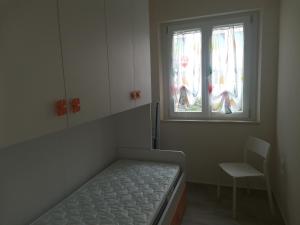 Cette petite chambre comprend un lit, une chaise et une fenêtre. dans l'établissement APPARTAMENTI SOLE-LUNA, à Francavilla al Mare