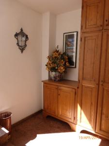 a room with a vase of flowers on a wooden cabinet at Auronzo Vacanze di Marina e Valter - Corte 12 in Auronzo di Cadore