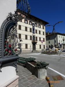 a building with a black fence next to a street at Auronzo Vacanze di Marina e Valter - Corte 12 in Auronzo di Cadore