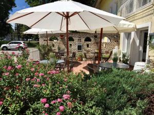 a patio with two tables and an umbrella and flowers at Hencz Vendégház in Balatonakarattya +5 photos