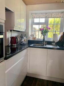 a kitchen with white cabinets and a sink and a window at Honeysuckle Cottage in Ilfracombe