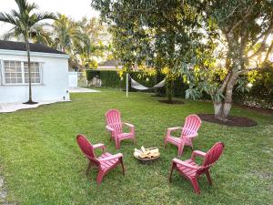four pink chairs and a fire pit in a yard at Home in Miami in Miami