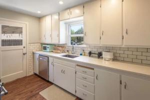 a kitchen with white cabinets and a sink and a window at Celebration Chalet! Quant, cozy, a few blocks from BSU and close to downtown Boise, Fireplace, 4 beds, and seating for 6 Pets Welcome! in Boise