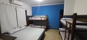 Zimmer mit 3 Etagenbetten und einer blauen Wand in der Unterkunft Melhor Custo x benefício - Tompell Pousada Bem-te-vi - Portaria só até 22 horas in Ponta Porã