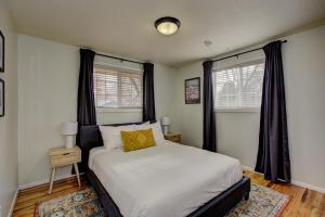 um quarto com uma cama e duas janelas em Sunset Home perfect for extended stays with fully fenced in yard, designated office, two living rooms, located across from Boise Foothills and close to Bogus Basin in Boise's North End em Boise