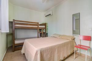 um pequeno quarto com uma cama e uma cadeira em Cobertura duplex c/piscina privativa,Praia Enseada no Guarujá