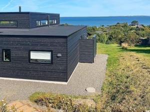 a black house with a view of the ocean at 10 person holiday home in Asn s in Asnæs