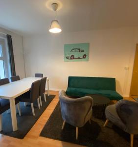 ein Esszimmer mit einem Tisch und Stühlen sowie einer grünen Couch in der Unterkunft Osthafen III in Berlin
