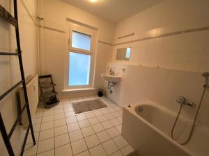 a white bathroom with a tub and a window at Osthafen III in Berlin