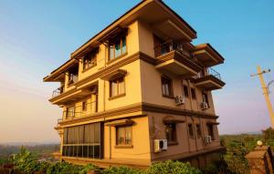 a tall yellow building with windows on a hill at Dona Paula Apartment in Dona Paula