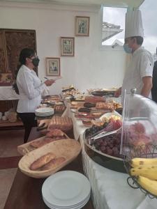 Dos personas con máscaras faciales parados detrás de un buffet de comida en City Art Hotel Silberstein en Quito