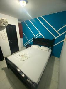 - un grand lit dans une chambre dotée d'un mur bleu dans l'établissement Residencias Piscis, à Barranquilla