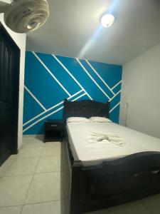 Cama en habitación con pared azul en Residencias Piscis, en Barranquilla