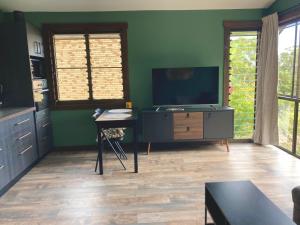 a living room with a flat screen tv and a table at Beautifully Elevated Treehouse Apartment in Buderim