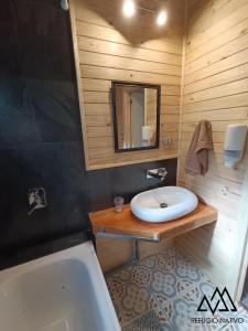 y baño con lavabo, bañera y espejo. en Refugio Nativo, en Nevados de Chillán