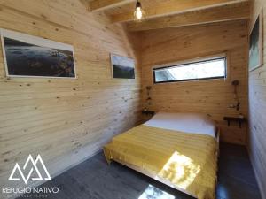 um quarto de um chalé de madeira com uma cama em Refugio Nativo em Nevados de Chillan
