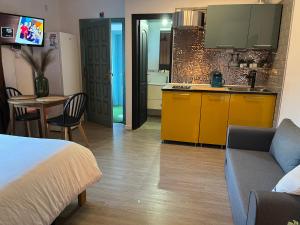 um quarto com uma cama e uma cozinha com armários amarelos em Acogedor estudio en la laguna em San Cristóbal de La Laguna