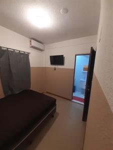 Habitación con cama, TV y ventana. en Melhor Custo x benefício - Tompell Pousada Bem-te-vi - Portaria só até 22 horas en Ponta Porã