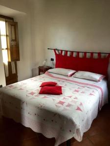 una camera con un letto con copriletto rosso e bianco di Hai mai dormito in un metato? a Corfino