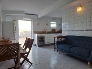 a living room with a blue couch and a kitchen at TI-WAIT in Sainte-Anne