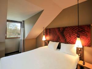 um quarto com uma grande cama branca e 2 almofadas em ibis Maisons Laffitte em Maisons-Laffitte