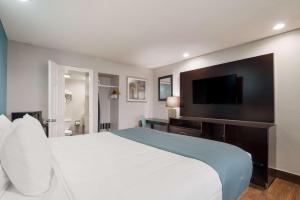 a bedroom with a large white bed and a flat screen tv at SureStay Hotel Laredo by Best Western in Laredo