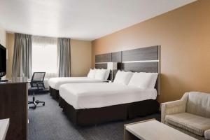 a hotel room with two beds and a chair at SureStay Hotel by Best Western Wells in Wells