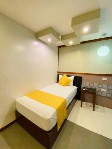 małą sypialnię z łóżkiem i żółtą poduszką w obiekcie Villa Rosita Hotel w mieście Naga