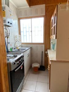 eine Küche mit einem Herd, einem Waschbecken und einem Fenster in der Unterkunft Cabañas Pino, Un lindo lugar de descanso in San Antonio