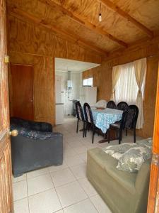 ein Wohnzimmer mit Tisch und Stühlen und eine Küche in der Unterkunft Cabañas Pino, Un lindo lugar de descanso in San Antonio