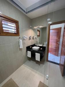 ein Bad mit einem Waschbecken und einer Glasdusche in der Unterkunft De Olho no Mar A única pousada de frente para o mar em Paracuru in Paracuru