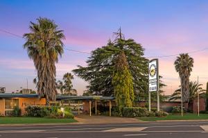 a gas station with palm trees in front of it at Plainsman Motel in Forbes