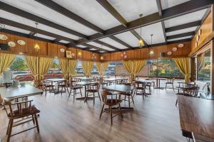 ein Restaurant mit Tischen, Stühlen und Fenstern in der Unterkunft Plainsman Motel in Forbes