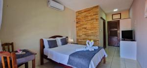 - une chambre avec un lit et une télévision dans l'établissement Hotel Pousada Sol & Lua, à Paracuru