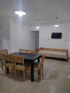 comedor con mesa y sillas y TV de pantalla plana en Departamentos Mora en General Alvear