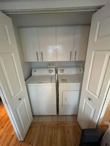 a small kitchen with white cabinets and a washer and dryer at Appartement Condo dans le vieux Québec in Quebec City