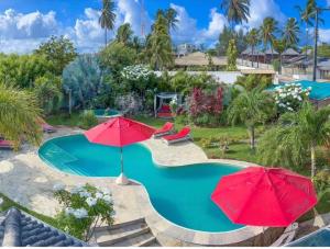 - une piscine avec deux parasols rouges dans l'établissement Xainã Pousada de Charme, à Cumbuco
