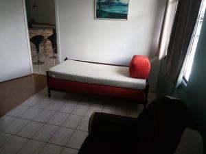 um quarto com uma cama e uma cadeira vermelha em Hospedagem com carinho! em Curitiba