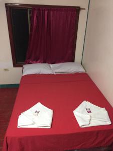 Una cama roja con dos toallas blancas. en Jackson Guest House, en Corn Island
