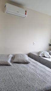 1 dormitorio con 2 camas y pared blanca en Casa temporada Florianópolis Sul da ilha, en Florianópolis