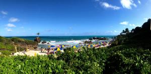 a group of people on a beach with umbrellas at Flat JACUMÃ LITORAL SUL PB in Jacumã